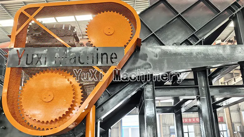 Detailed shot of the large exposed gear mechanism and protective mesh covering of the industrial Hammer Mill Shredder.