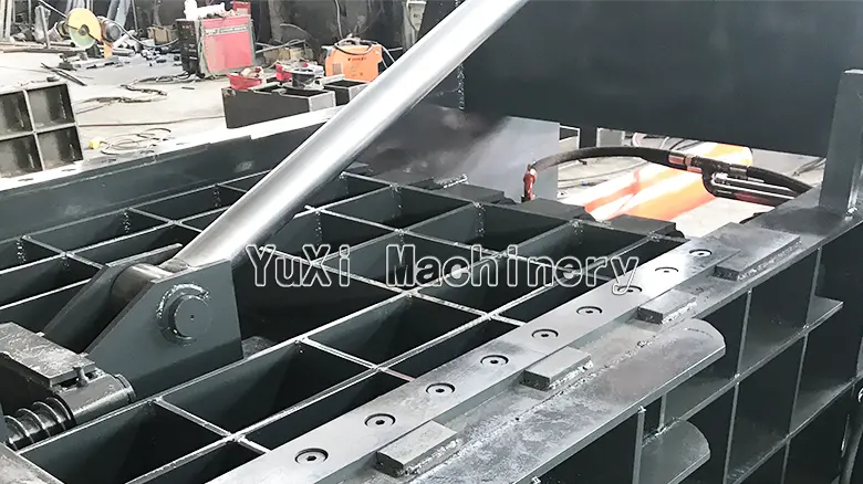 Close-up detail of the metal baler's durable compaction chamber and hydraulic cylinder linkage